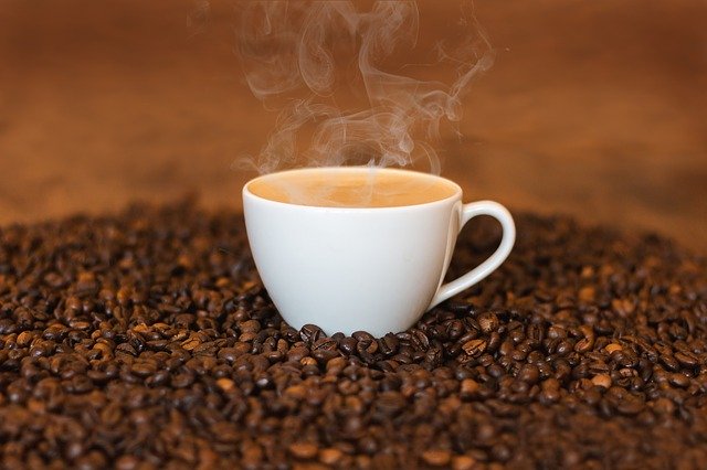 steaming cup of coffee set in coffee beans